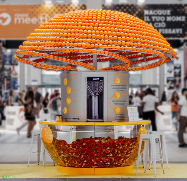 Машина, отжимая сок, перерабатывает апельсиновые корки в стаканчики